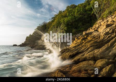 Vagues s'écrasant sur les rochers de Chahue Beach dans les Bahias de Huatulco, au Mexique. Une vitesse d'obturation lente donne un aspect soyeux à l'eau. Banque D'Images