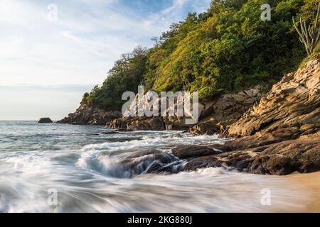 Vagues arrivant à terre sur la plage de Chahue dans les Bahias de Huatulco, au Mexique. Une vitesse d'obturation lente donne un aspect soyeux à l'eau. Banque D'Images