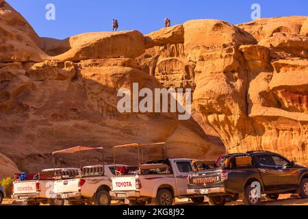 Jordanie, Wadi Rum - 2 novembre 2022: Voitures de tour bédouin en jeep debout près du pont de pierre d'Um Frouth, désert avec falaise rocheuse montagne en arrière-plan Banque D'Images