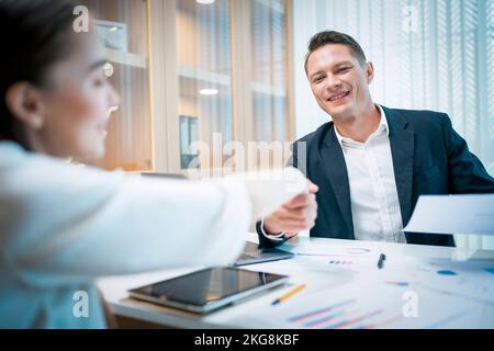 Un homme d'affaires caucasien vérifie la main avec une jeune femme d'affaires attirante après avoir fini les affaires au pouvoir. Concept d'entreprise et de réussite Banque D'Images