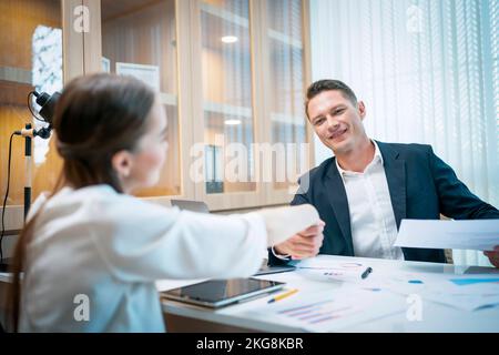 Un homme d'affaires caucasien vérifie la main avec une jeune femme d'affaires attirante après avoir fini les affaires au pouvoir. Concept d'entreprise et de réussite Banque D'Images