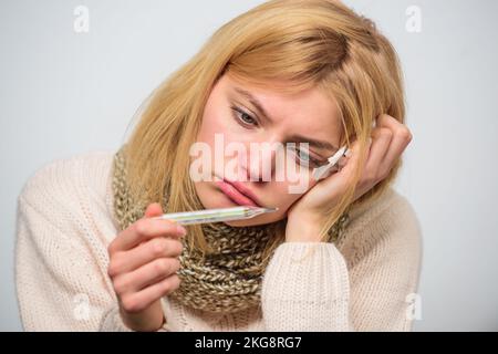 Concept haute température. La femme se sent mal éternuée. Une fille en foulard tient le thermomètre et le mouchoir de près. Mesurer la température. Fièvre de pause Banque D'Images