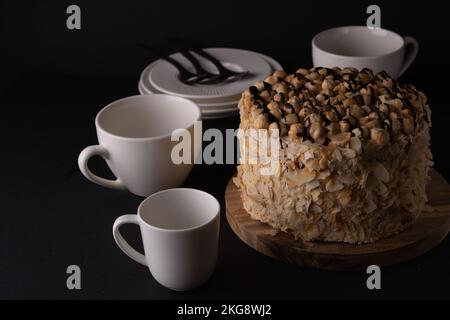 photo de gâteau de noyer entier et vaisselle blanche sur un fond noir Banque D'Images