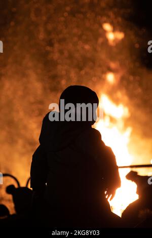 Les enfants sur les épaules de leurs parents se sont présentés devant un feu de joie torant lors de l'événement annuel de feu d'artifice de la Table ronde de Bicester. Banque D'Images