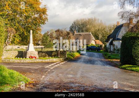 Le centre du village de Tarrant Monkton à Dorset, en Angleterre, montrant le mémorial de guerre et les chalets de chaume, en automne ou en automne. Banque D'Images