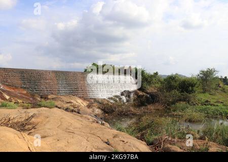 Vue sur un barrage débordant fait de matériaux de construction naturels comme des briques entourées de greeneries et de rochers Banque D'Images