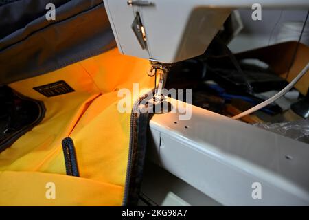 Machine à coudre électrique surpiqûres le long de la fermeture éclair sur le tissu jaune du sac lourd Banque D'Images