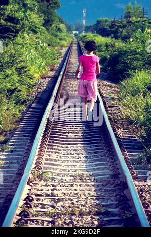 HUA HIN, THAÏLANDE - 19 SEPTEMBRE 2010 : une jeune fille thaïlandaise marche le long d'une voie ferrée transportant une parcelle enveloppée Banque D'Images