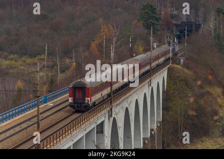 Train international rapide sur le pont Miru près de la gare de Tisnov en Moravie en automne le jour sombre Banque D'Images