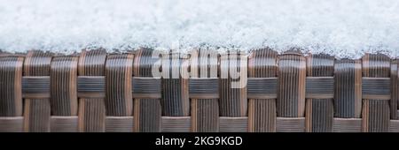 Entretien et stockage des meubles de jardin en hiver. texture des meubles de rue en hiver. Rotin artificiel recouvert de neige en gros plan. Banque D'Images