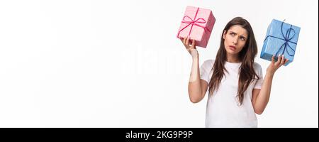 Célébration, fêtes et cadeaux concept. Hmmm intéressant ce qui à l'intérieur. Portrait de curieux jeune fille d'anniversaire secouant des boîtes-cadeaux essayant de Banque D'Images