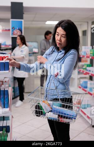 Client âgé mettant une boîte de pilules dans le panier pour acheter des médicaments sur ordonnance et des produits médicaux. Client prenant des médicaments pharmaceutiques paquet pour guérir la maladie, les fournitures de santé capsules. Banque D'Images
