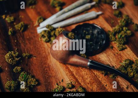 Tuyau en bois pour fumer sur la table contre le fond d'un bourgeon de cbd sativa ou indica tgk. Joints. Banque D'Images