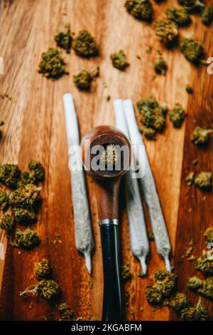 Tuyau en bois pour fumer sur la table contre le fond d'un bourgeon de cbd sativa ou indica tgk. Joints. Banque D'Images