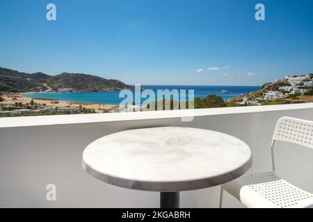 Vue incroyable depuis un balcon avec une chaise et une table donnant sur la célèbre plage Mylopotas à iOS Grèce Banque D'Images
