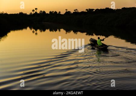 Aratuipe, Bahia, Brésil - 31 août 2018 : un pêcheur pagayant son canoë sur le fleuve Jaguaripe, ville d'Aratuipe, au coucher du soleil. Banque D'Images