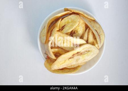 Chips de banane dans une assiette blanche sur un fond blanc prêt à la vente Banque D'Images