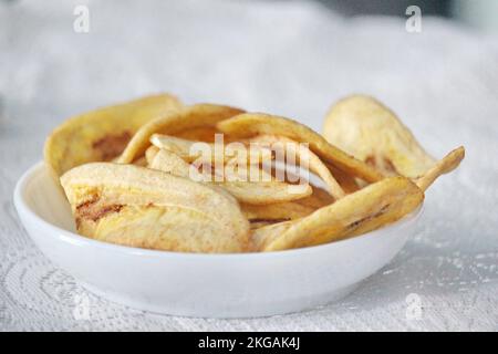 Chips de banane dans une assiette blanche sur un fond blanc prêt à la vente Banque D'Images