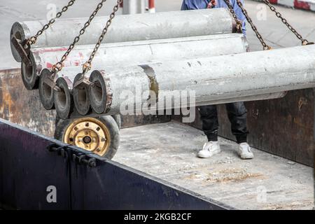 Une grue lève les tubes de béton de l'espace de chargement d'un chariot Banque D'Images