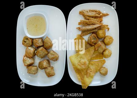 Découpe de rouleaux de viande de crabe frits (Hoi JO)et de boulettes frits sur noir isolé. Banque D'Images