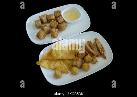 Découpe de rouleaux de viande de crabe frits (Hoi JO)et de boulettes frits sur noir isolé. Banque D'Images