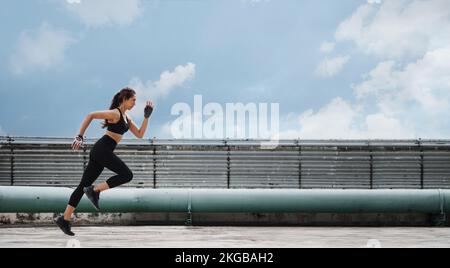 Femme athlète en train de courir et de faire de l'exercice de fente sur le toit. Banque D'Images