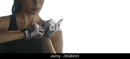 Une femme met des gants de fitness pour faire de l'exercice à la salle de gym. Banque D'Images