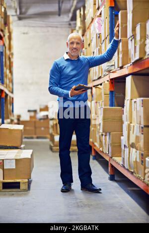 HES en charge. Un homme debout à côté de rayonnages industriels avec des boîtes. Banque D'Images