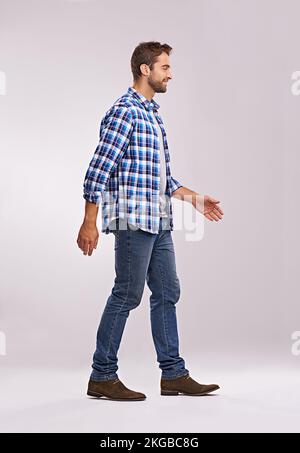 J'ai des lieux à visiter. Plein studio de prise de vue d'un homme marchant sur un fond gris. Banque D'Images