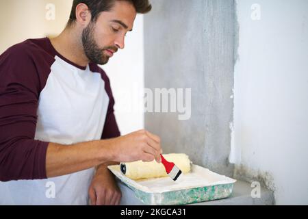 Améliorations à domicile. un jeune homme peint un mur à l'intérieur. Banque D'Images