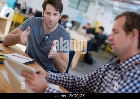 Ils prennent une bonne idée et la rendent grande. collègues qui parlent ensemble sur une tablette numérique à un bureau dans un grand bureau. Banque D'Images