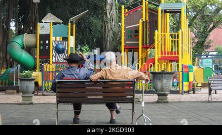 Amitié avec la vieillesse. Trois adultes s'assoient dans des chaises dans la ville d'Alun-alun Malang, à l'est de Java. MALANG, INDONÉSIE. 08 MARS 2018. Banque D'Images