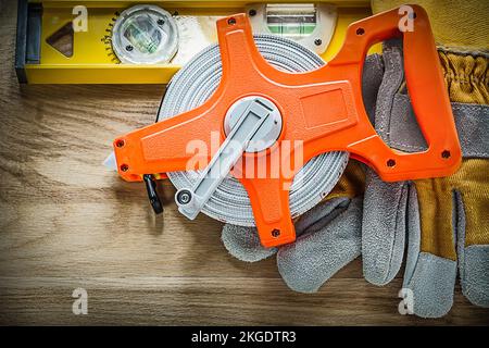 Gants de protection de niveau de construction mètre ruban sur panneau en bois. Banque D'Images