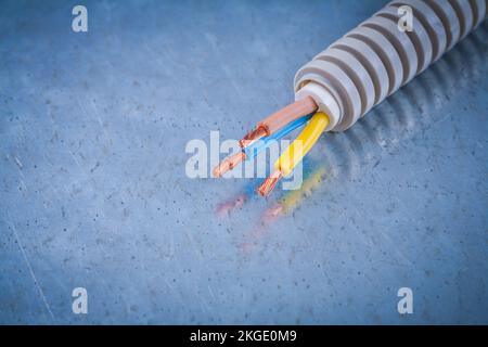 Câbles en cuivre de protection de fils électriques ondulés sur une surface métallique rayée. Banque D'Images