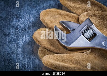 Gants de sécurité en cuir avec clé réglable en acier inoxydable sur fond métallique rayé concept de construction. Banque D'Images