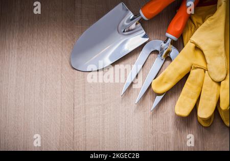 Gants de sécurité en cuir fourche à truelle et bêche à main sur planche de bois concept de jardinage. Banque D'Images