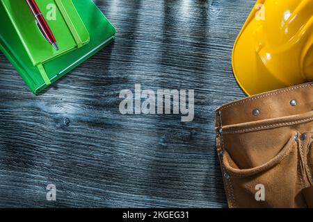 Carnets stylo casque dur cuir ceinture à outils sur panneau en bois. Banque D'Images