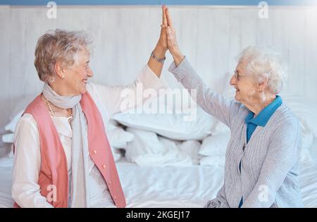Femme âgée, amis haut cinq et assis dans la chambre avec le sourire, heureux ou ensemble dans la maison de soins infirmiers. Les femmes âgées, les meilleurs amis et le bonheur avec Banque D'Images