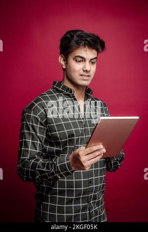 Jeune homme d'affaires indien souriant, professionnel arabe, indépendant, gestionnaire de bijoux, et homme d'affaires tenant une tablette et debout dans un arrière-plan de studio Banque D'Images