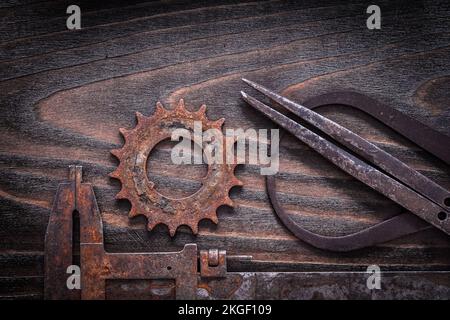 Étriers de mesure anciens rouillés avec roue dentée sur fond de bois sombre vintage concept de construction. Banque D'Images