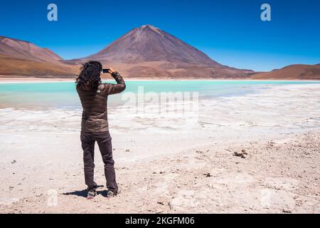 Elle photographie la Laguna Verde (lagune verte) avec le volcan Licancabur en arrière-plan à la Réserve nationale de faune andine Eduardo Avaroa, Bolivie Banque D'Images
