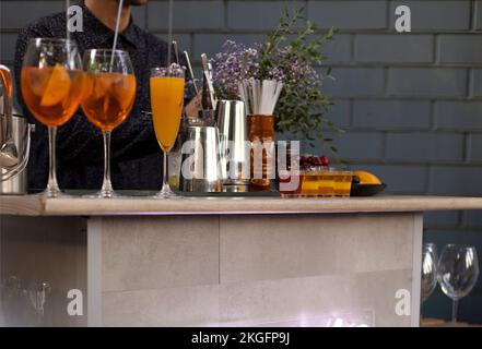 Verres de cocktails au bar. Le barman verse un verre de vin mousseux avec de l'alcool rouge. Barman pré-ardu apéritif spritz cocktail en plein air en été Banque D'Images