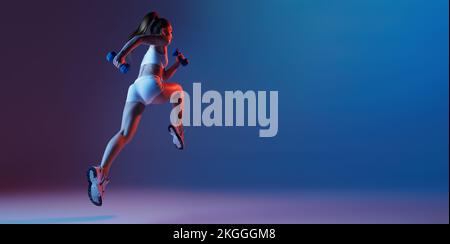 Vue arrière de la jeune fille sportive en blanc sportswear courant loin isolé sur fond bleu dégradé violet dans la lumière néon. Fitness, passe-temps, santé Banque D'Images