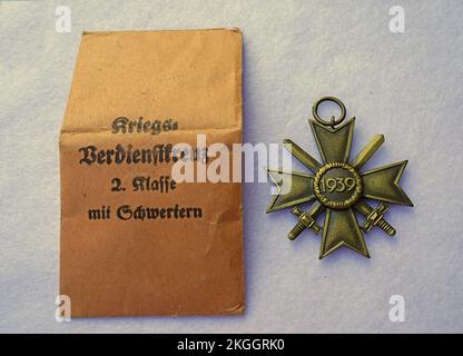 Une ancienne médaille allemande de guerre de la Seconde Guerre mondiale avec le sac de papier marron correspondant. Croix du mérite de la guerre Banque D'Images