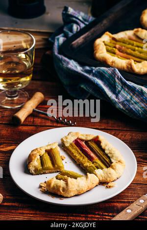 Tranches de mini-galette de rhubarbe sur une assiette blanche avec un verre de vin Banque D'Images