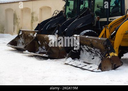 Les engins de terrassement à usage intensif garés les uns à côté des autres pour déplacer la neige après le blizzard. Excavatrices industrielles déneigement des trottoirs. Banque D'Images