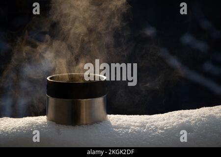 Gros plan de la tasse thermos avec une boisson chaude à l'extérieur sur la neige. Personne Banque D'Images
