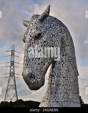 Duke, l'un des Kelpies au parc Helix Country Park, Falkirk, en Écosse, avec un pylône électrique en arrière-plan. Banque D'Images