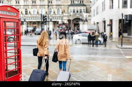 UK, Londres, deux amis à la découverte de la ville, qui arrivent avec des sacs trolley Banque D'Images