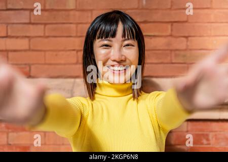 Bonne jeune femme portant un col de cygne jaune devant un mur de briques Banque D'Images